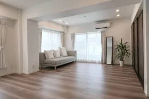 The main room of JG Studio located in Tokyo, Shibuya. An open space featuring a gray sofa and a balcony, with natural light pouring in through large windows.