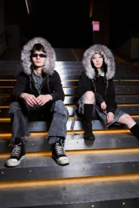 Two models in faux-fur hooded streetwear posing on illuminated stairs in Shibuya, Tokyo.