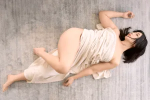 Boudoir-style portrait of model Rioka reclining in draped ivory fabric, shot by JG in his Shibuya studio in Tokyo.