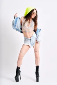 Fashion editorial photo shot at JG Studio Tokyo with a model in denim shorts and chainmail top against a white studio backdrop.