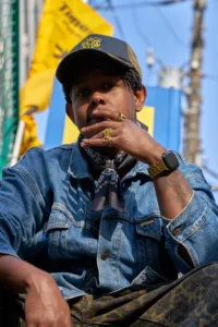 Street portrait of a man in a denim jacket and bandana with gold rings and cap, shot during JG's Shibuya photo tour.